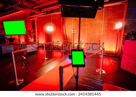 360 spinner photo booth setup with a red carpet, lighting equipment, and a screen in a red-lit event space.