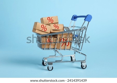 Discount offer. Boxes with percent signs in mini shopping cart on light blue background
