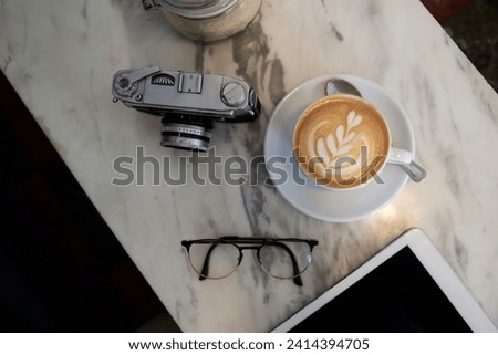 From above view of a coffee cup analogue camera and glasses on a marble table