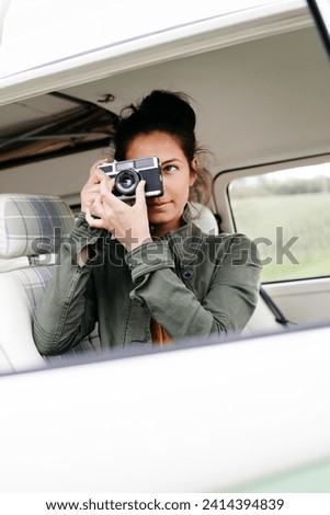 Young woman sitting in camper- taking pictures
