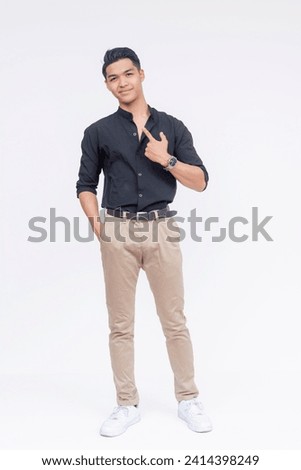 Stylish young Filipino man posing on a white background, exuding confidence and trendy casual style. Pointing to himself. Royalty-Free Stock Photo #2414398249