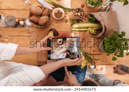 Friends cooking together taking picture of prepared vegetables with tablet- top view