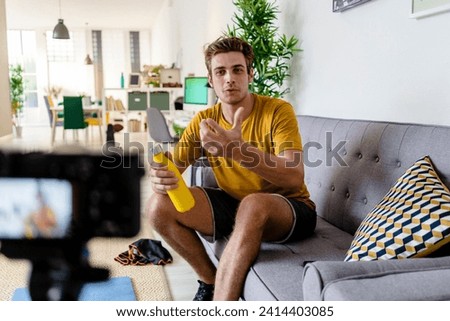 Fitness trainer live streaming fitness session while sitting on sofa at home