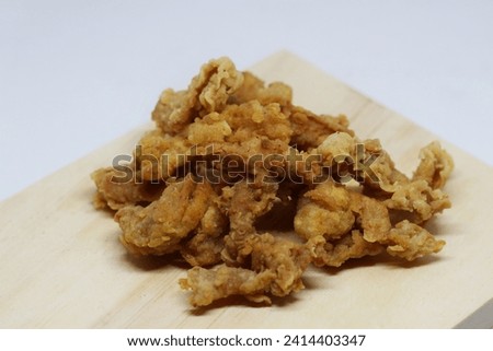 Usus krispi, chicken intestine chips Typical food is made from chicken intestines that are fried in flour until dry on a wooden tray isolated on a white background.