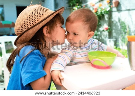 Little girl kissing her younger sister at backyard in spring