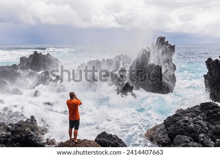 Usa- hawaii- big island- laupahoehoe beach park-man taking pictures of breaking surf at the rocky coast