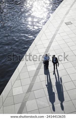 Two businessmen walking and talking at the riverbank Royalty-Free Stock Photo #2414413635