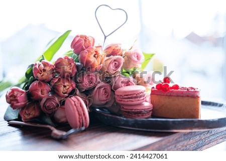 Beautiful pink roses and tulips with sweet pastrys. Concept background for mother's day, valentine's day and weddings. Close-up with short depth of field and space for text.