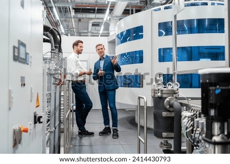 Two businessmen talking in a modern factory Royalty-Free Stock Photo #2414430793