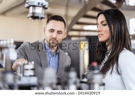 Businessman and businesswoman examining workpieces in factory Royalty-Free Stock Photo #2414430919