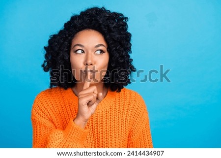 Photo portrait of pretty young girl keep secret look empty space dressed stylish knitted orange outfit isolated on blue color background