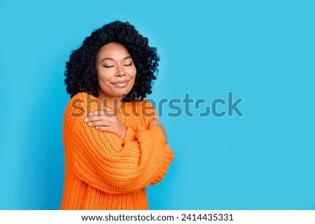 Photo portrait of pretty young girl embrace self enjoy warmth wear trendy knitwear orange outfit isolated on blue color background Royalty-Free Stock Photo #2414435331
