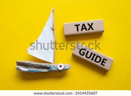 Tax Guide symbol. Concept word Tax Guide on wooden blocks. Beautiful yellow background with boat. Business and Tax Guide concept. Copy space