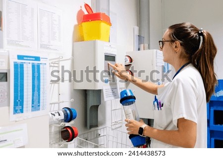 Female doctor using pneumatic tube system while standing in hospital Royalty-Free Stock Photo #2414438573