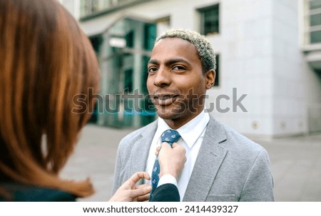 Young businesswoman fastening tie of young businessman