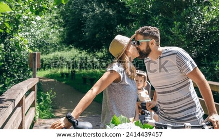 Couple with bicycles kissing with little daughter looking at them