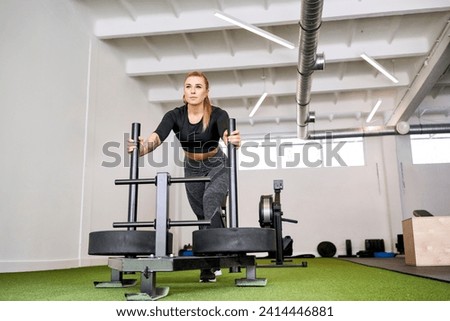 Woman pushing weight sled at gym Royalty-Free Stock Photo #2414446881