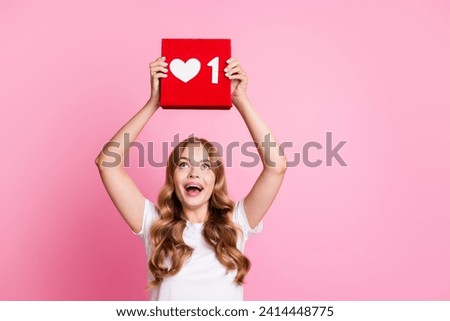 Photo of woman in white t shirt holding red icon click button follow youtube channel raised hands up isolated on pink color background