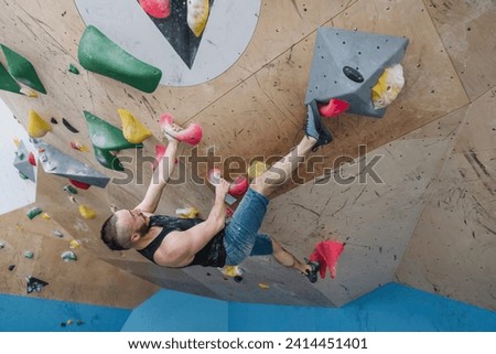 Man bouldering in climbing gym Royalty-Free Stock Photo #2414451401