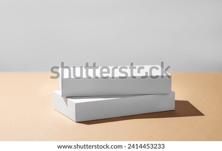 Empty podium for product. Minimal two white boxes on a beige background with hard shadow.  Showcase concept with stage for product presentation, sale or advertising banner. Copy space.