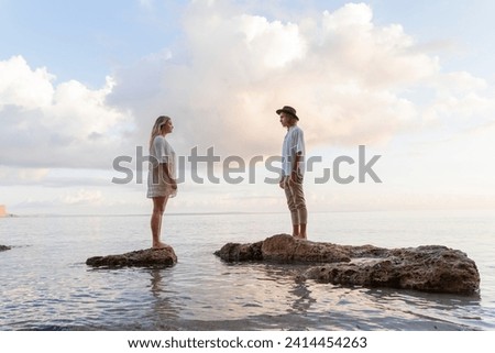 Young couple standing on rocks in front of the sea- ibiza- balearic islands- spain Royalty-Free Stock Photo #2414454263