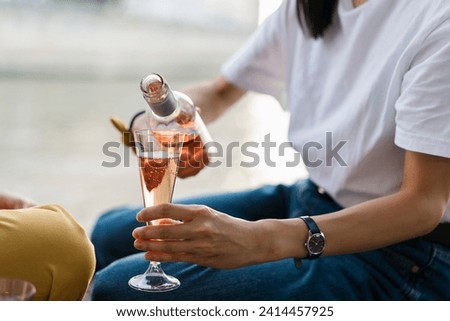Close-up of woman pouring in sparkling blush wine Royalty-Free Stock Photo #2414457925