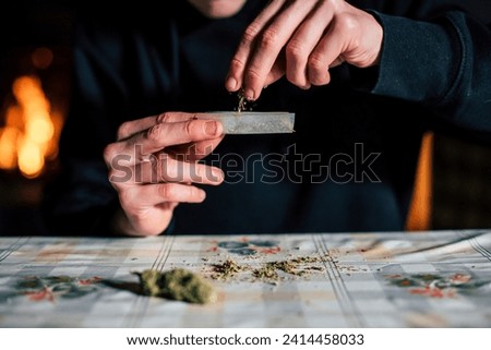 Close-up of a man's hands preparing marihuana joint Royalty-Free Stock Photo #2414458033
