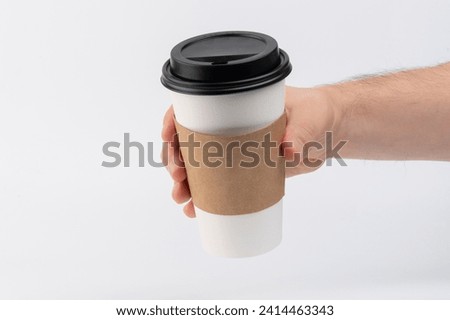 Paper cup for tea or coffee in hand isolated on white studio background