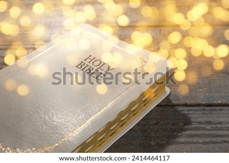 Holy Bible on wooden table, bokeh effect