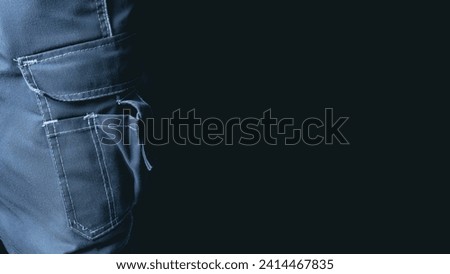 Worker in work pants. Pocket close-up on a dark background. Banner with place for text.