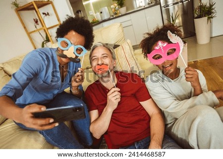 Happy family with party props taking selfie by smartphone sitting on sofa at home 