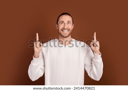 Photo of dreamy guy dressed white pullover looking pointing two fingers up empty space isolated brown color background