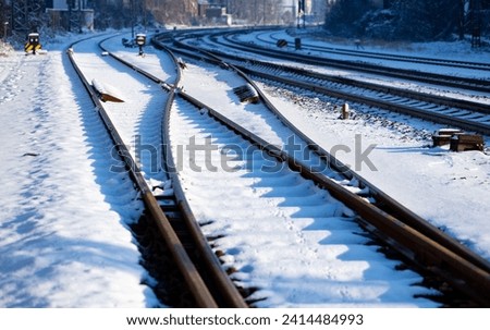 Frosted railway tracks with switches, rails, thresholds and screws covered with snow on a sunny winter day near Letmathe station. Railroad infrastructure on german main line from Hagen to Siegen. Royalty-Free Stock Photo #2414484993