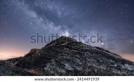 Perched atop a lonely peak, a group of adventurers become silhouettes against the sprawling tapestry of the Milky Way, in a moment that feels both vast and intimate.
 Royalty-Free Stock Photo #2414491939