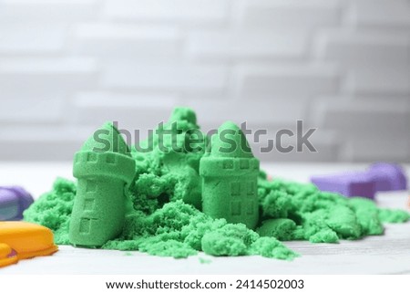 Castle figures made of green kinetic sand on white table, closeup Royalty-Free Stock Photo #2414502003