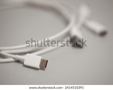 USB type C male plug of white cable on baclground. Shallow depth of field.