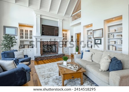Living room interior with wooden beams hardwood flooring area rug furnishings sofa fireplace cabinets bohemian style houseplants arm chairs in natural colors Royalty-Free Stock Photo #2414518295
