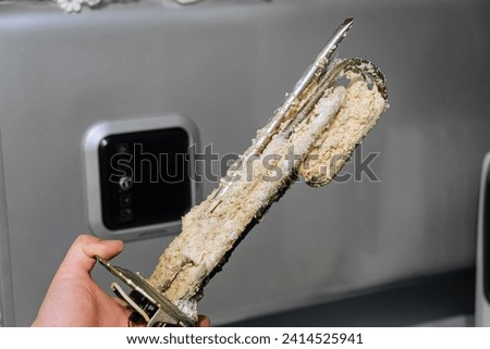 Heating element of an electric water heater with a rusty anode and a tube covered with scale Royalty-Free Stock Photo #2414525941