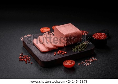 Delicious canned pink ham with salt, spices and herbs on a dark concrete background Royalty-Free Stock Photo #2414543879