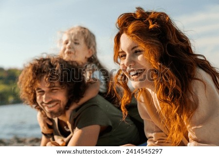 Close up of happy family having fun relax and lying on a blanket on sunny beach. Parents father and mother and daughter kid child spending time together outdoors