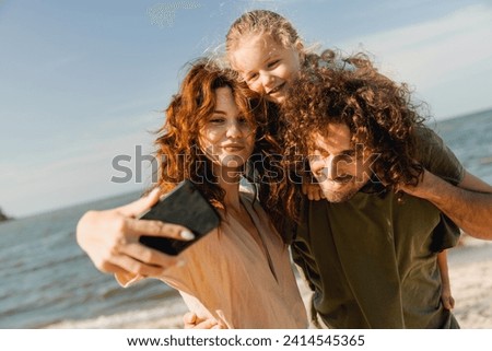 Happy family taking selfie and spending good time at the beach together. Caucasian father and mother spouses taking selfie photo on smartphone walking along river lake