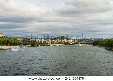 Landscape view of Coimbra bridge upon Mondego river in Portugal with a summer cloudy sky day Royalty-Free Stock Photo #2414554879