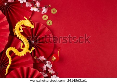 Respecting and upholding the traditions of a Chinese New Year. Top view photo of gold dragon, folding fans, sakura bloom, traditional coins on red background with promo space Royalty-Free Stock Photo #2414563161