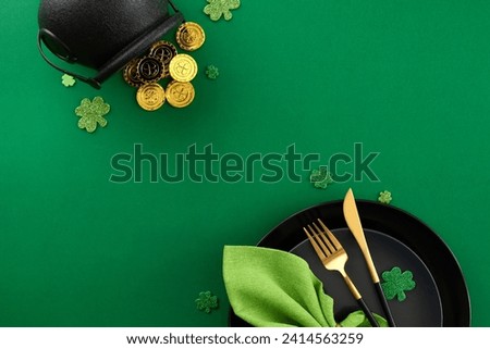 Welcoming St. Patrick's Day at the table. Top view shot of plates, cutlery, green napkin, pot with coins, present, clovers on green background with promo zone