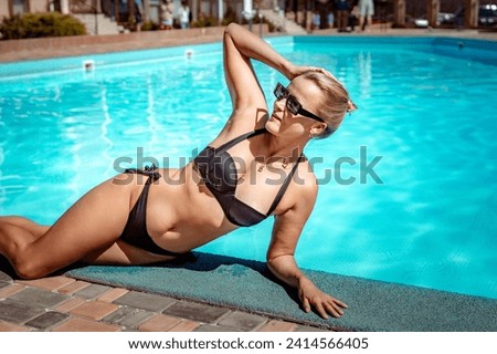Bikini-clad woman enjoys poolside relaxation. Poolside ambiance. Capturing woman's relaxed time near pool.