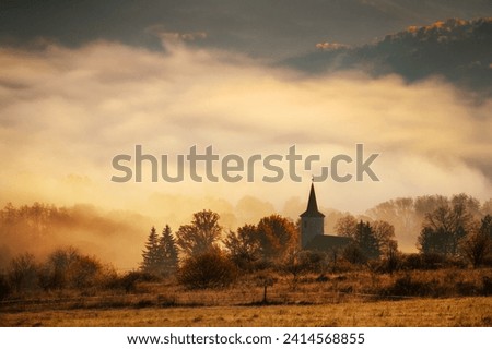 Picture with the motif of the Christian faith, the silhouette of the Christian church, the morning sun and the fog in the background. Indian summer, orange colors of sunrise