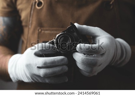 Photographer wearing white gloves holding a folding camera in his hand