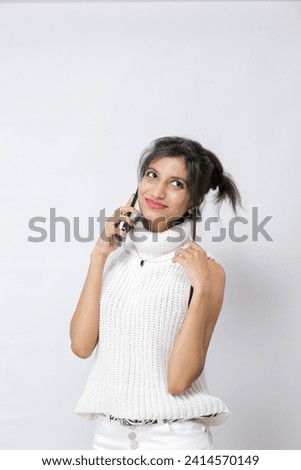 Portrait of a smiling Pakistani casual woman holding smartphone , on a happy call over white background