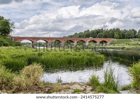 Kuldigas old brick bridge across the Venta river was built in 1874 and is the longest bridge of this kind of road bridge in Europe. Near it is the widest waterfall in the Baltics on the River Venta. Royalty-Free Stock Photo #2414575277