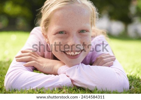 Happy, portrait and girl child lying in grass for fun, play and adventure in nature. Face, smile and kid in garden with positive attitude, mindset and excited for exploring, learning or weekend break